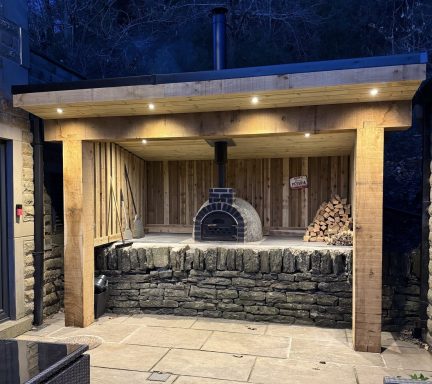 Outdoor kitchen shelter built around an existing pizza oven