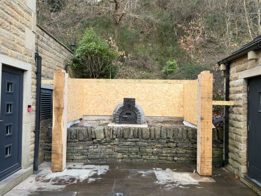 Covered oak outdoor cooking area built around a pizza oven