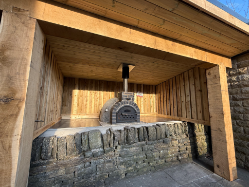 Bespoke outdoor shelter surrounding a built-in pizza oven