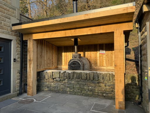 Oak-framed outdoor kitchen shelter designed around a pizza oven